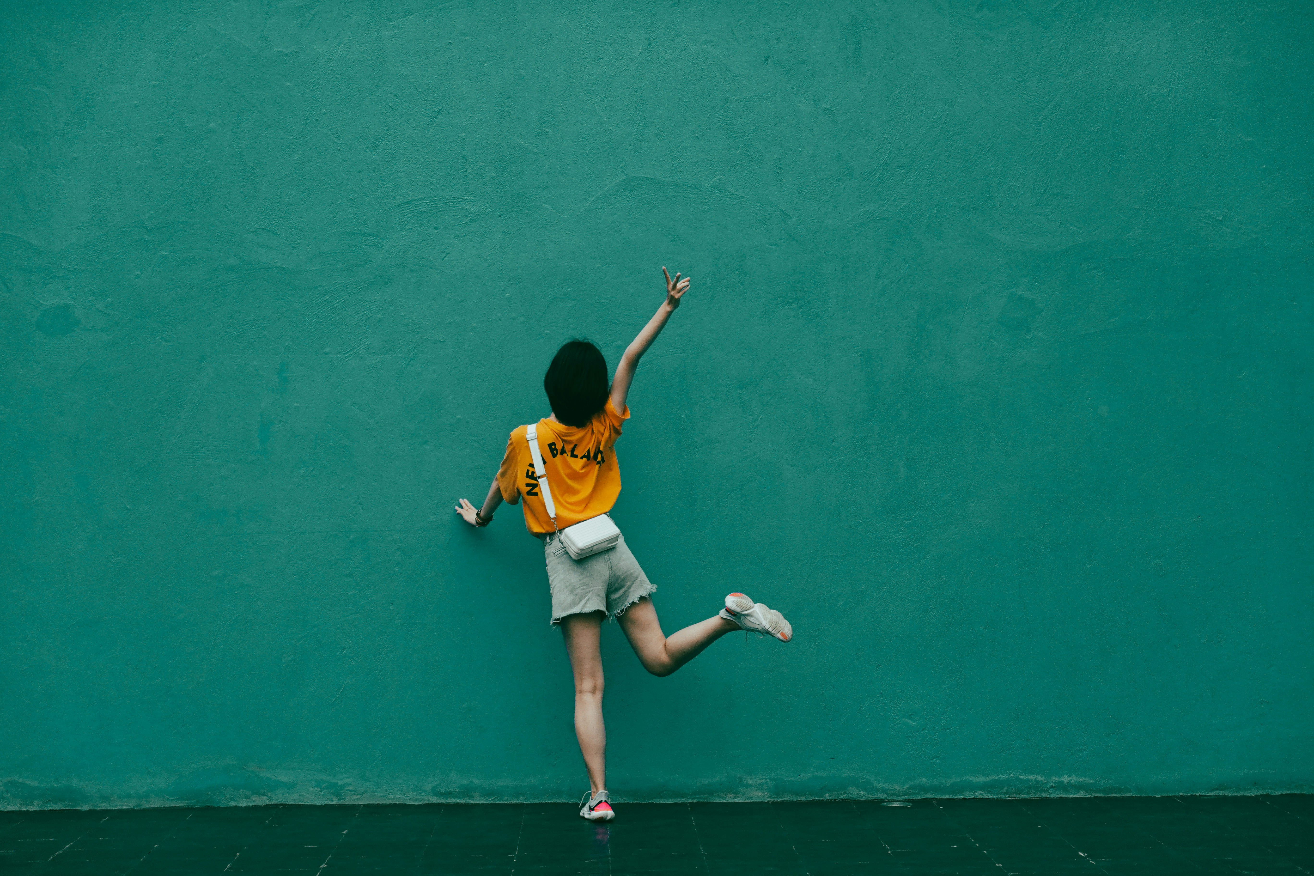 boy in yellow t-shirt and white shorts running on green concrete floor